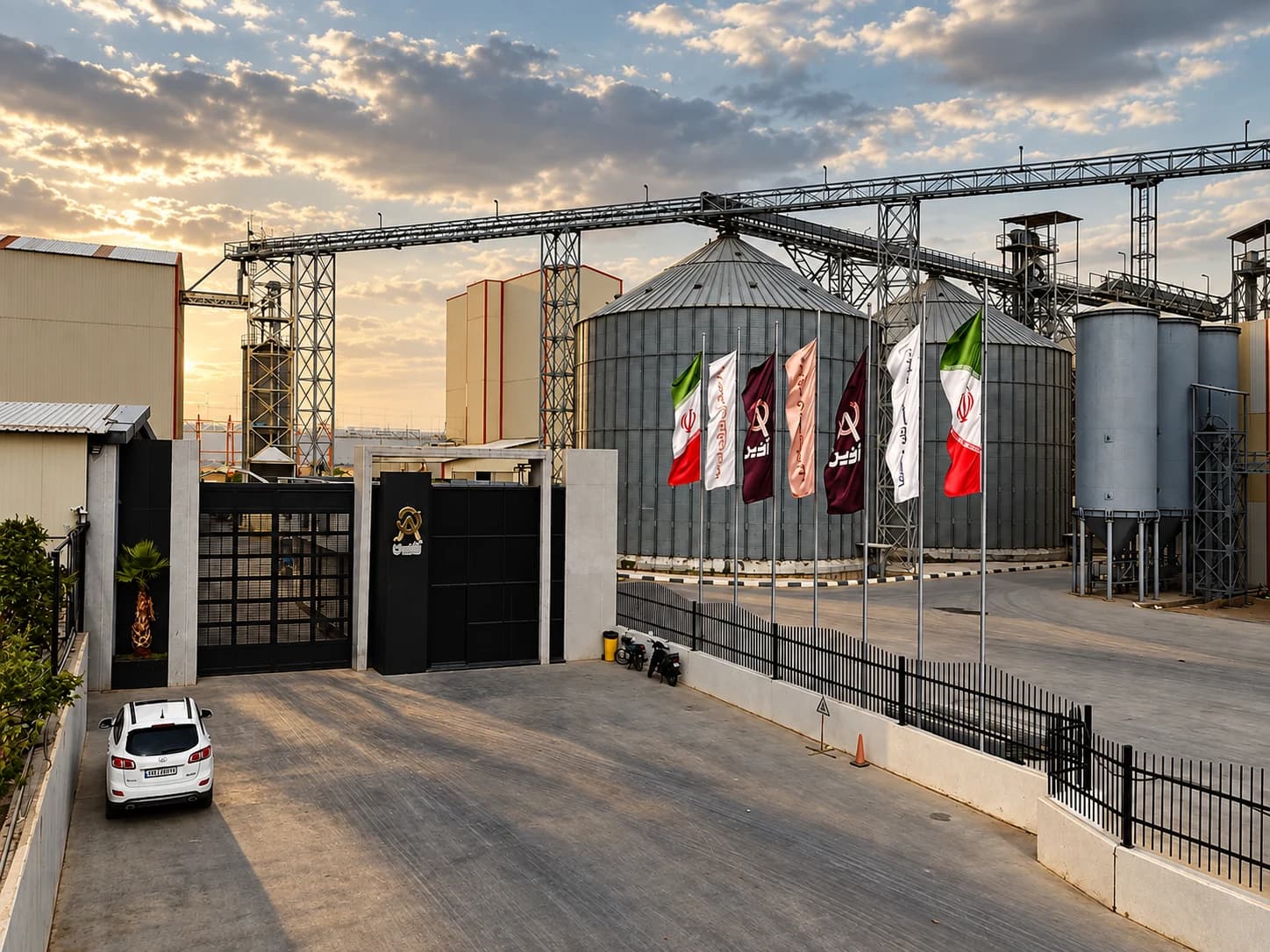 Plant main gate with company flags flying beside the silos